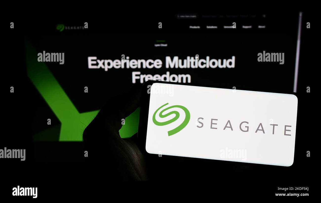Person holding smartphone with logo of US data storage company Seagate Technology LLC on screen in front of website. Focus on phone display. Stock Photo