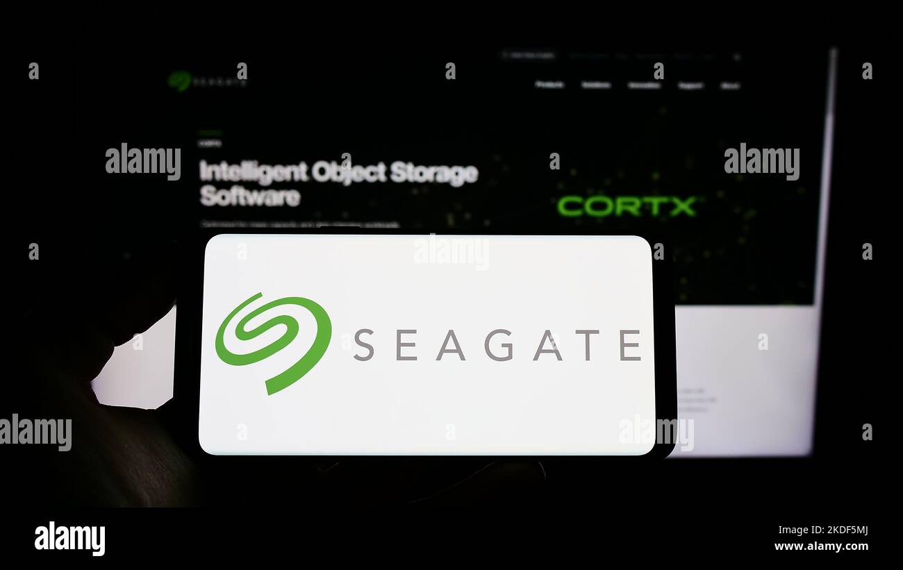 Person holding cellphone with logo of American data storage company Seagate Technology LLC on screen in front of webpage. Focus on phone display. Stock Photo