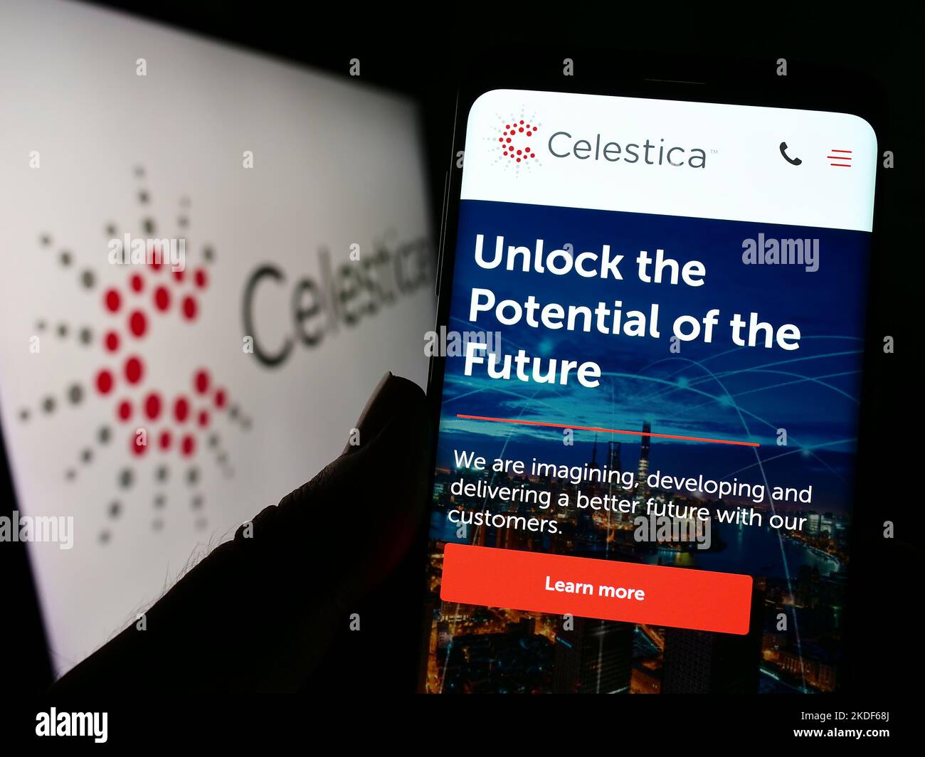 Person holding cellphone with website of Canadian electronics company Celestica Inc. on screen in front of logo. Focus on center of phone display. Stock Photo