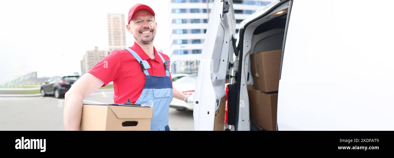 Smiling courier with parcels near delivery van Stock Photo