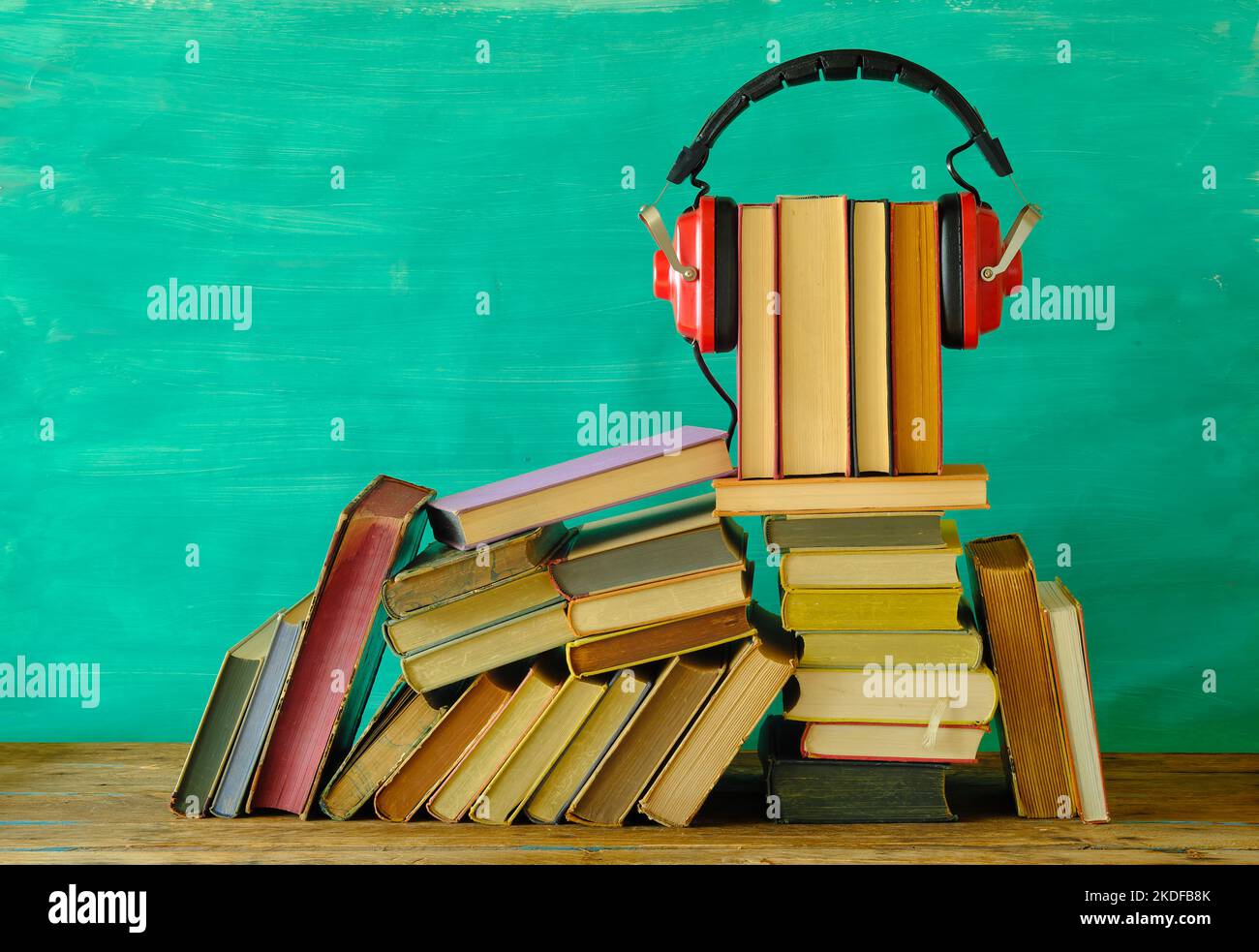 audio book concept with stack of books and vintage red headphone on teal background,good copy space. Stock Photo