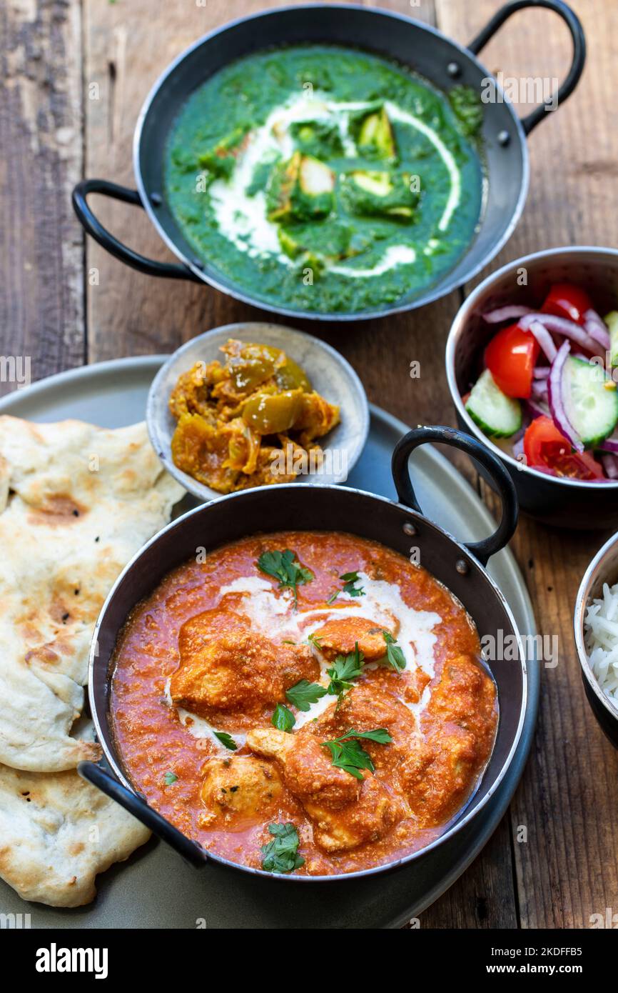 Butter chicken, saag paneer, toamto salad and naan bread Stock Photo