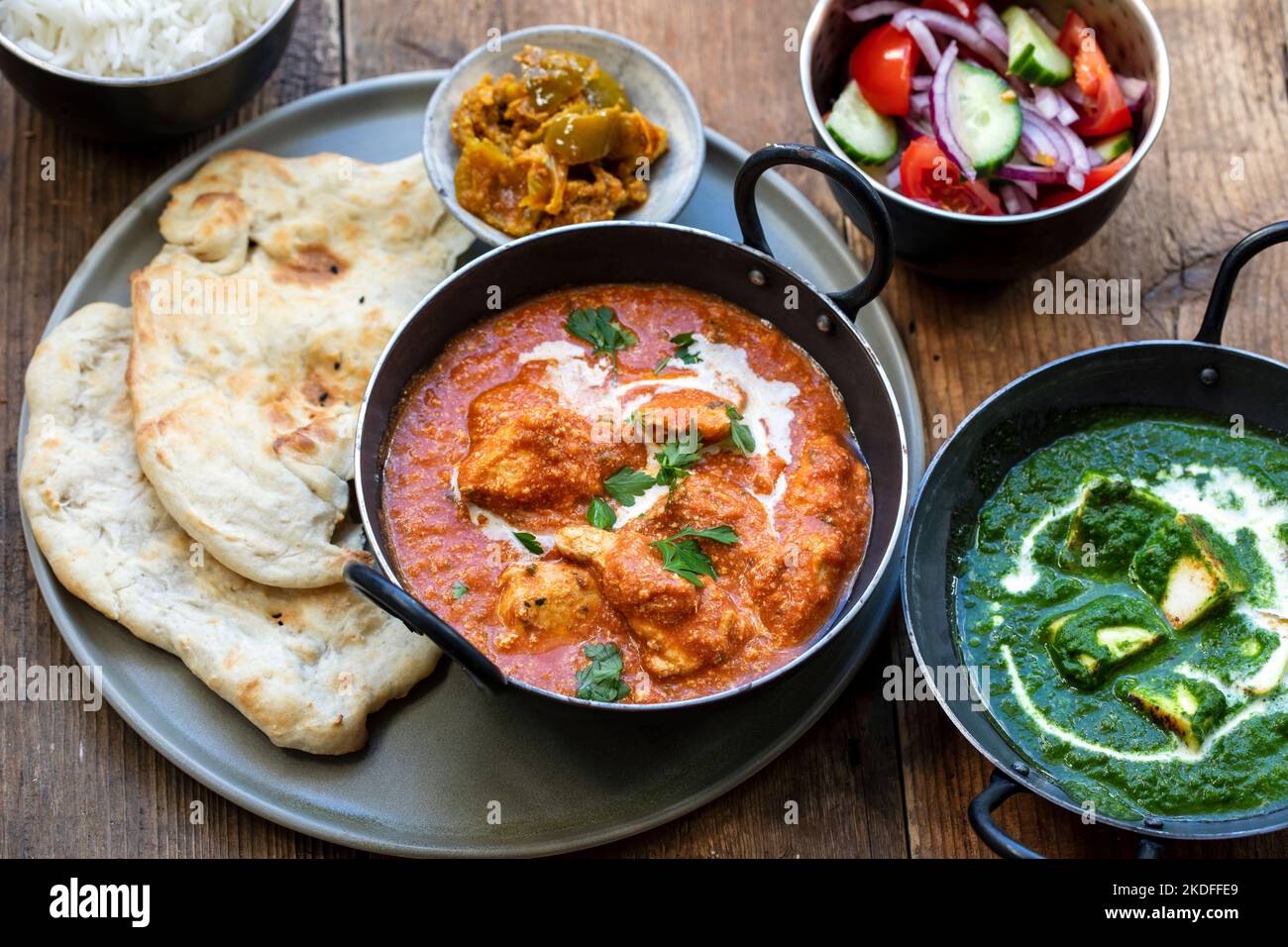 Butter chicken, saag paneer, toamto salad and naan bread Stock Photo