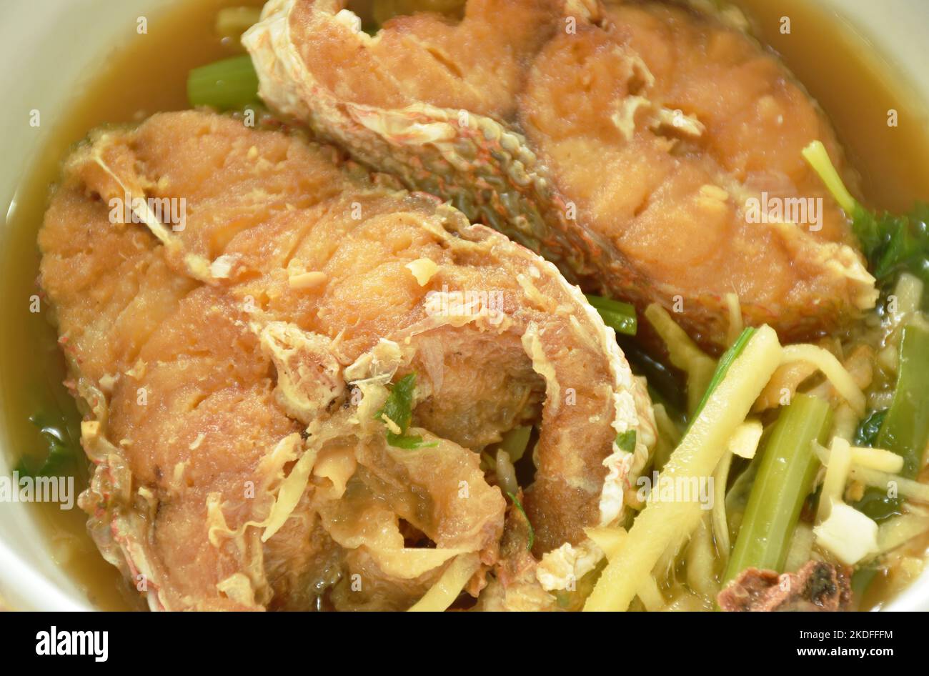 deep fried bass fish slice dressing soy sauce and spring onion on bowl