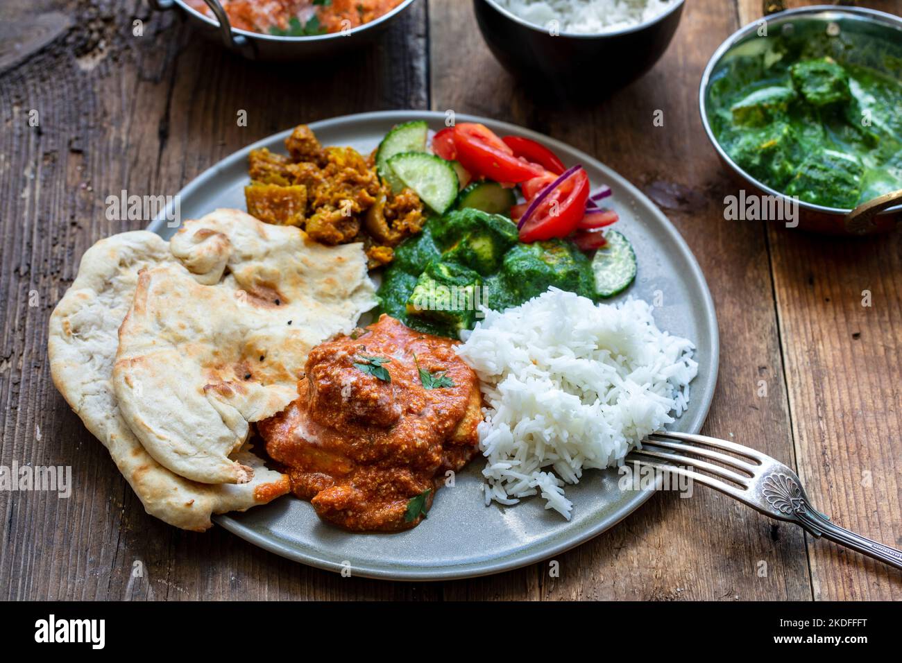 Butter chicken, saag paneer, toamto salad and naan bread Stock Photo