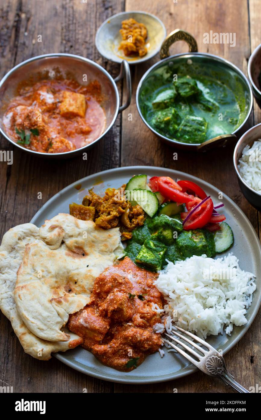 Butter chicken, saag paneer, toamto salad and naan bread Stock Photo