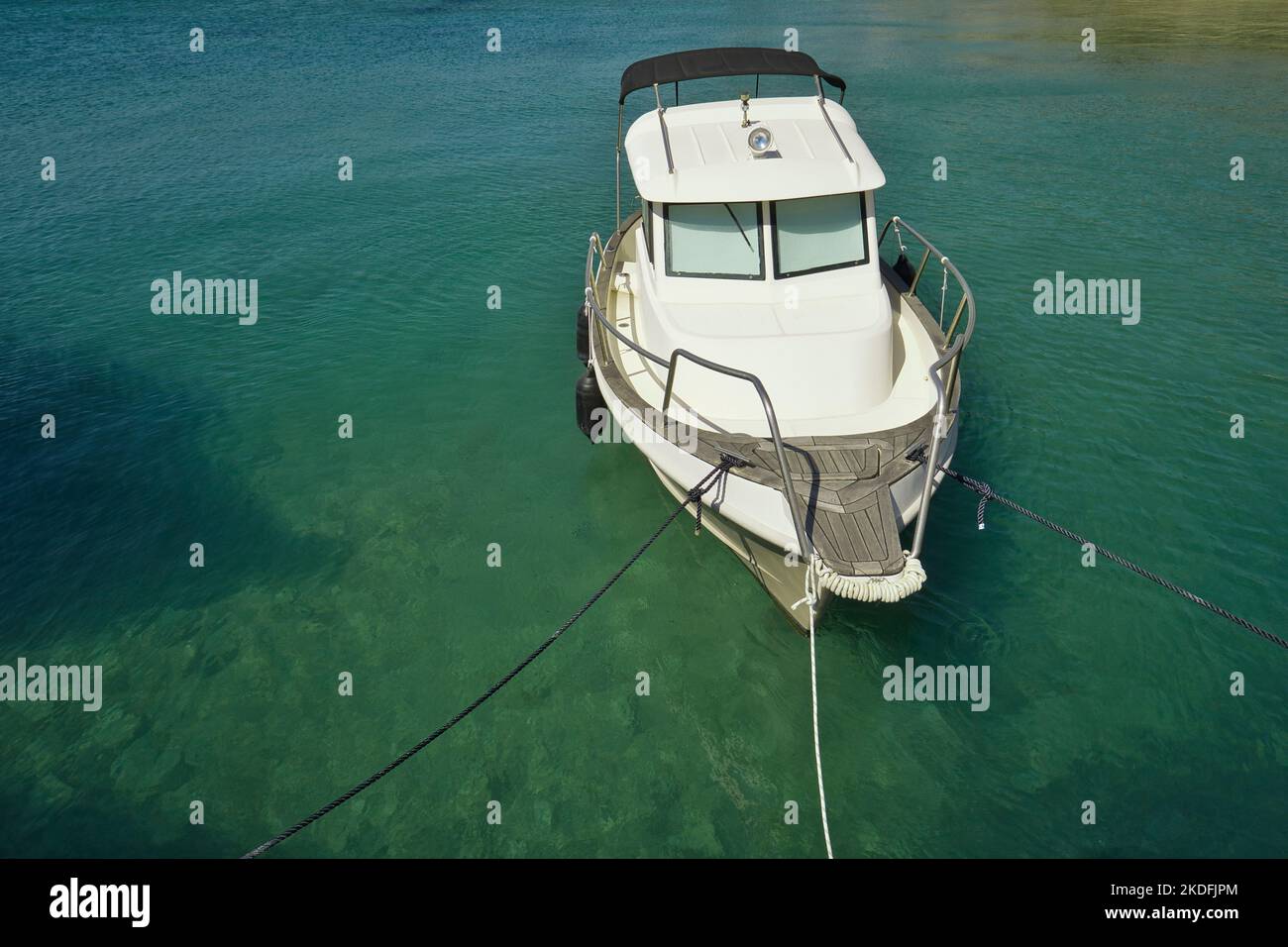 A small boat with cabin and sun roof anchors in the harbor Stock Photo