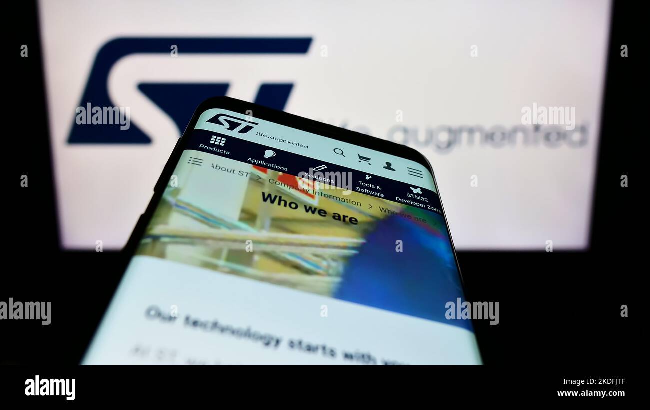 Mobile phone with website of semiconductor company STMicroelectronics NV on screen in front of business logo. Focus on top-left of phone display. Stock Photo