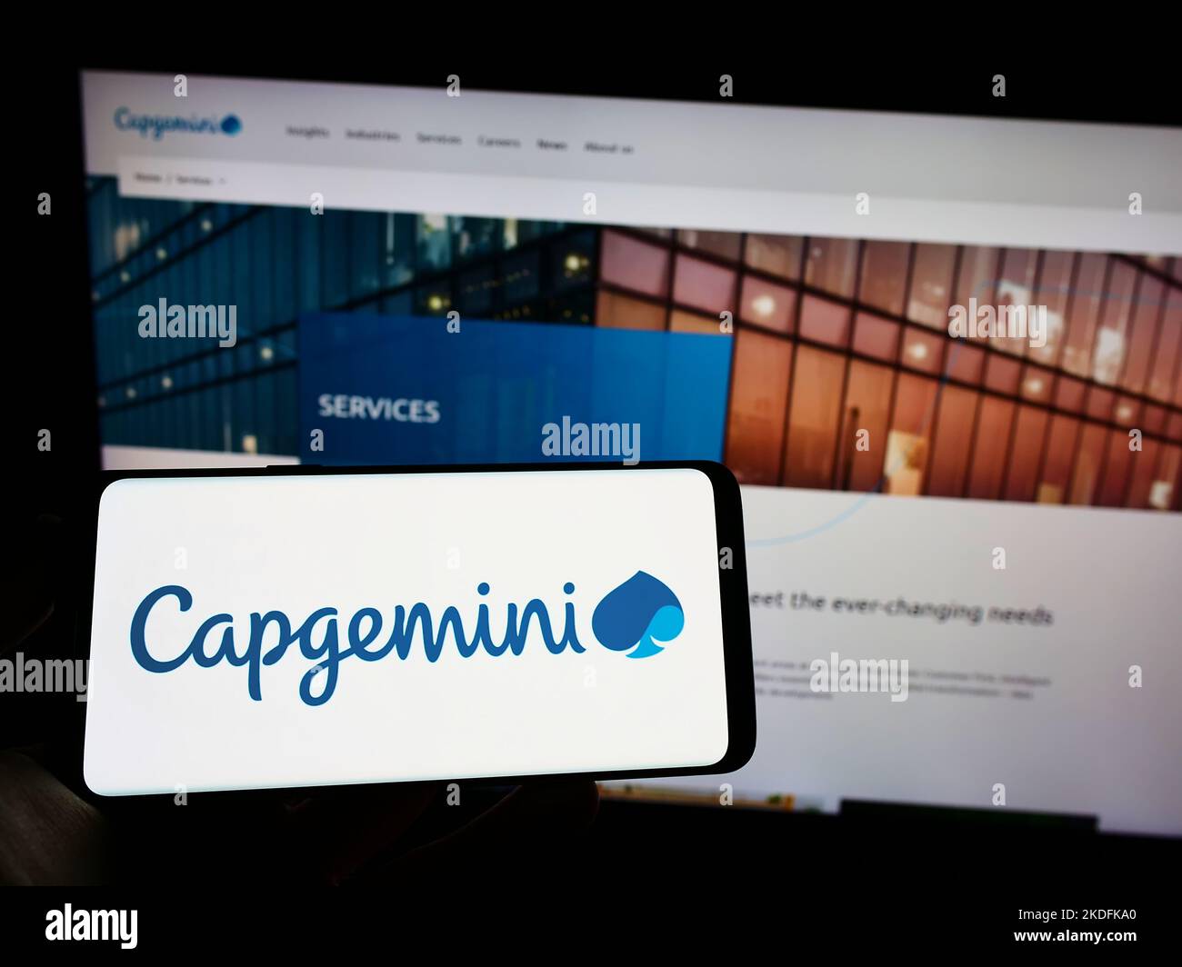 Person holding cellphone with logo of information technology company Capgemini SE on screen in front of business webpage. Focus on phone display. Stock Photo
