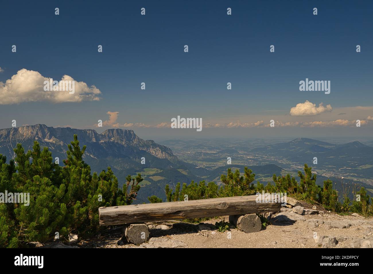 A bench made of wood with a beautiful view of the valley of Berchtesgaden Stock Photo