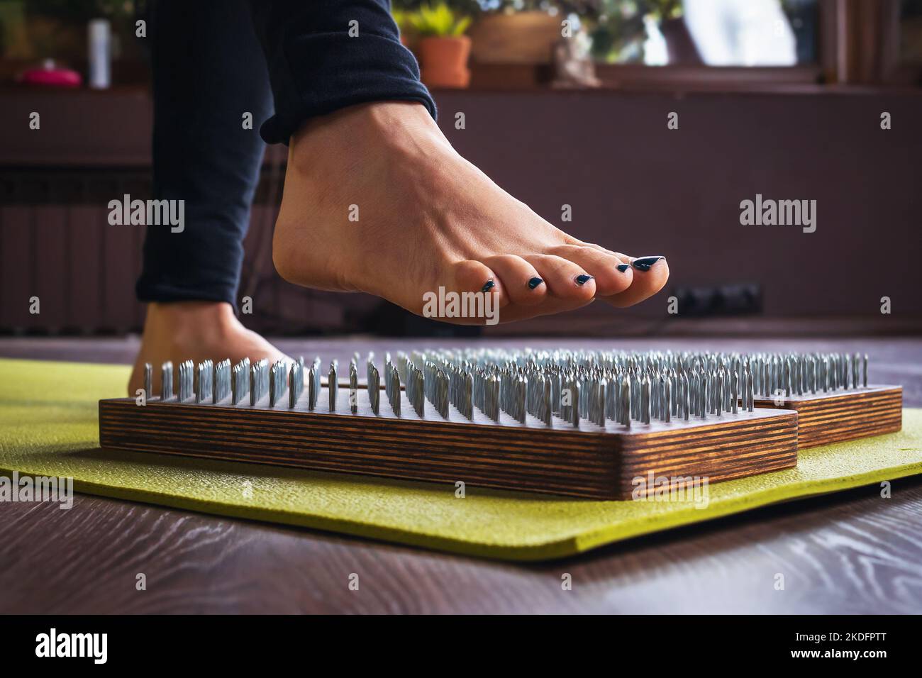 A woman practicing yoga, performs an exercise on a sadhu board with nails, a concept on the