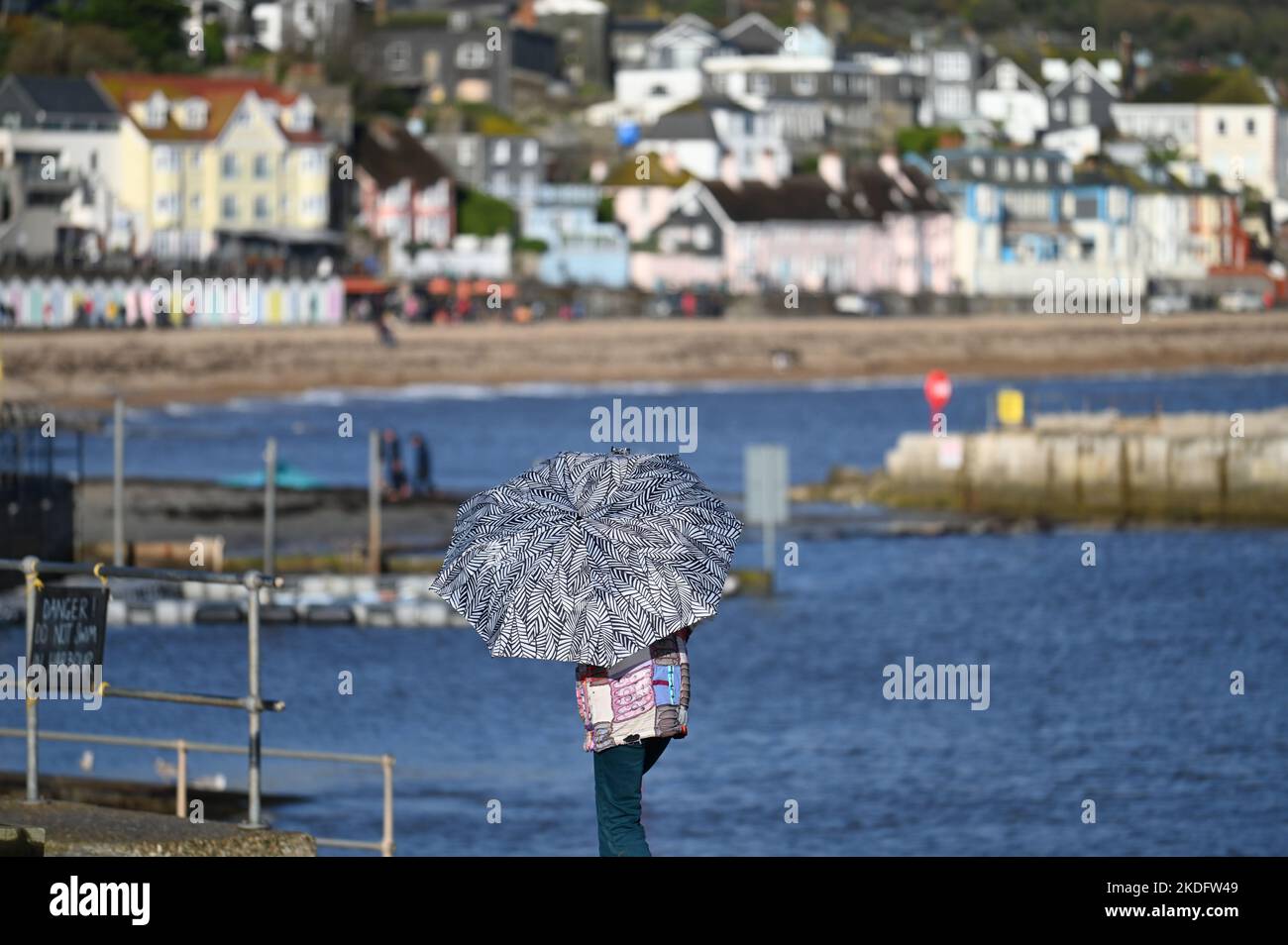 Lyme Regis, UK. 06th Nov, 2022. ON a very windy afternoon with mixed weather a person is seen with black and white umbrella blown inside out. Picture Credit: Robert Timoney/Alamy Live News Stock Photo