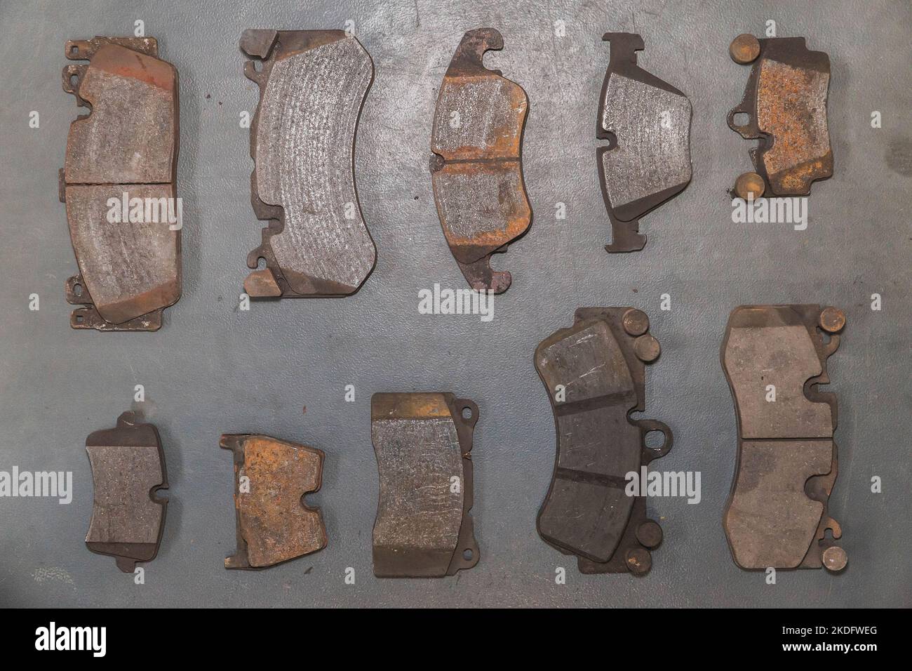 Brake pads of different sizes are on the floor in the workshop Stock Photo