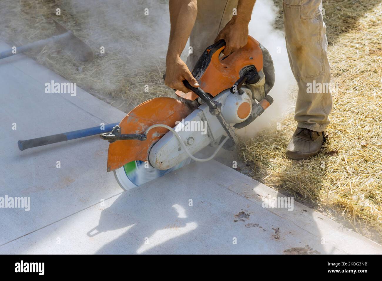Construction worker cutting concrete sidewalk using diamond blade saw machine Stock Photo