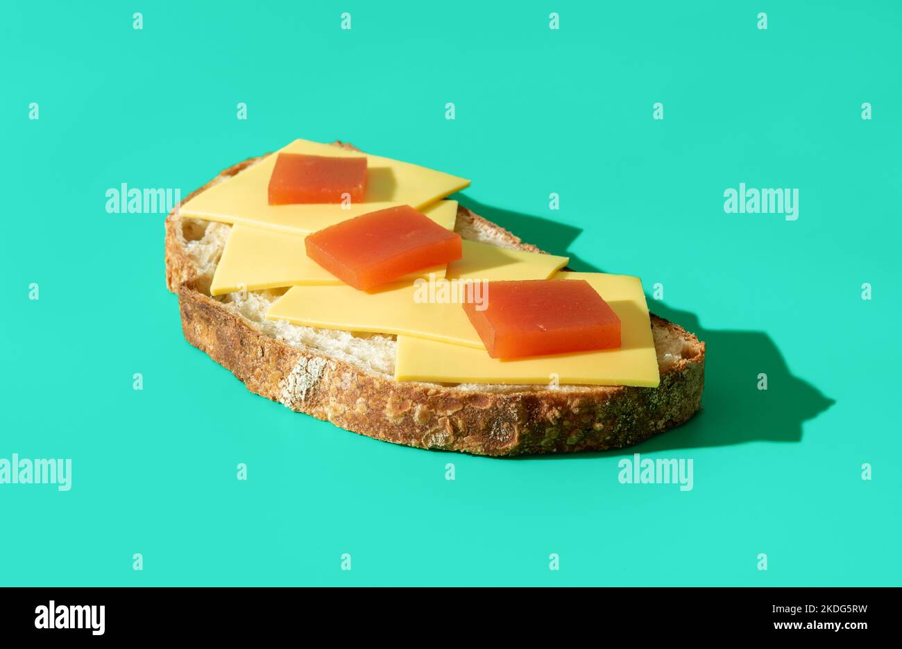 Close-up with a single slice of homemade bread with cheese and quince marmalade on top of it. Cheese and quince jelly on a slice of bread, minimalist Stock Photo