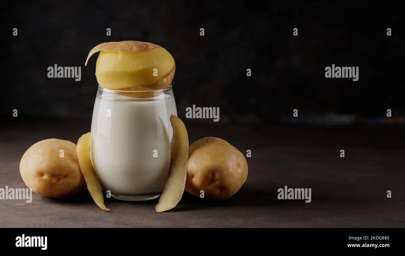 Potato milk in glass and potato peels. Lactose free vegetable milk and