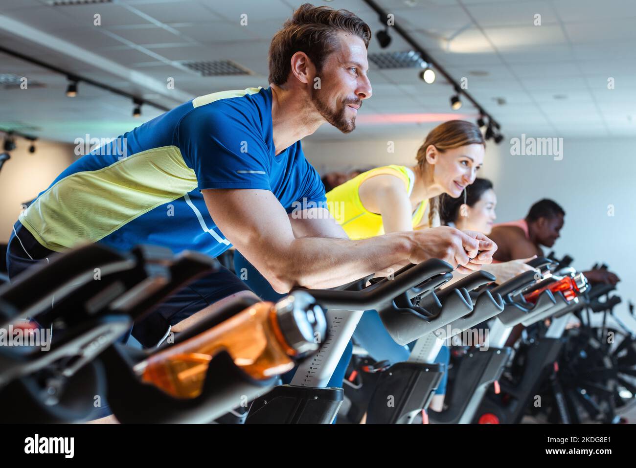 Caucasian man and her friends on fitness bike in gym Stock Photo