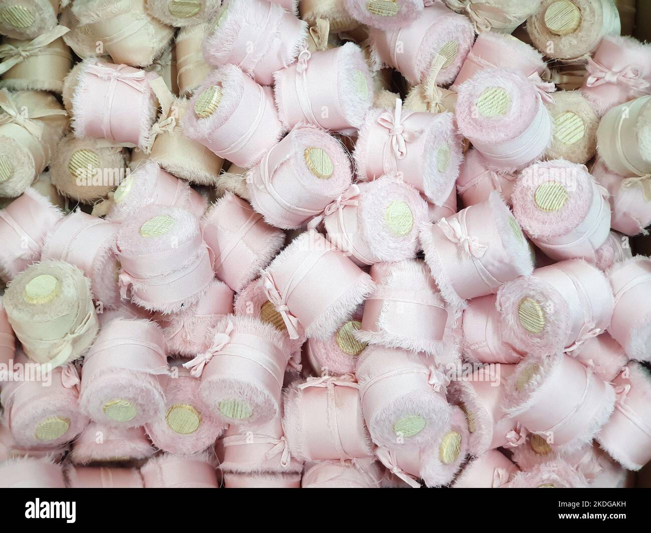 Close-up of light pink silk ribbons with wooden spools a lot. Texture background. Stock Photo
