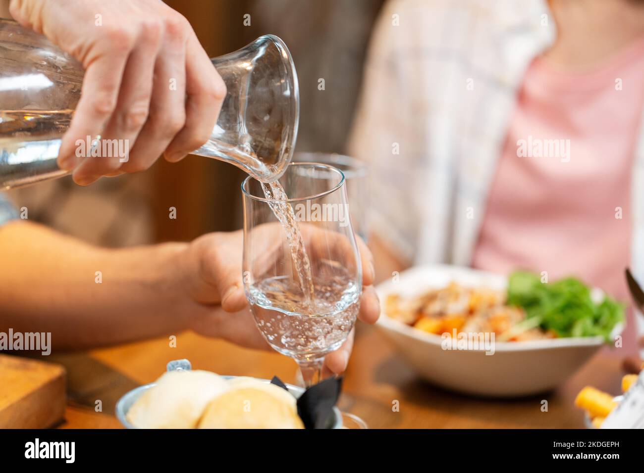 hands pouring water to glass at restaurant Stock Photo