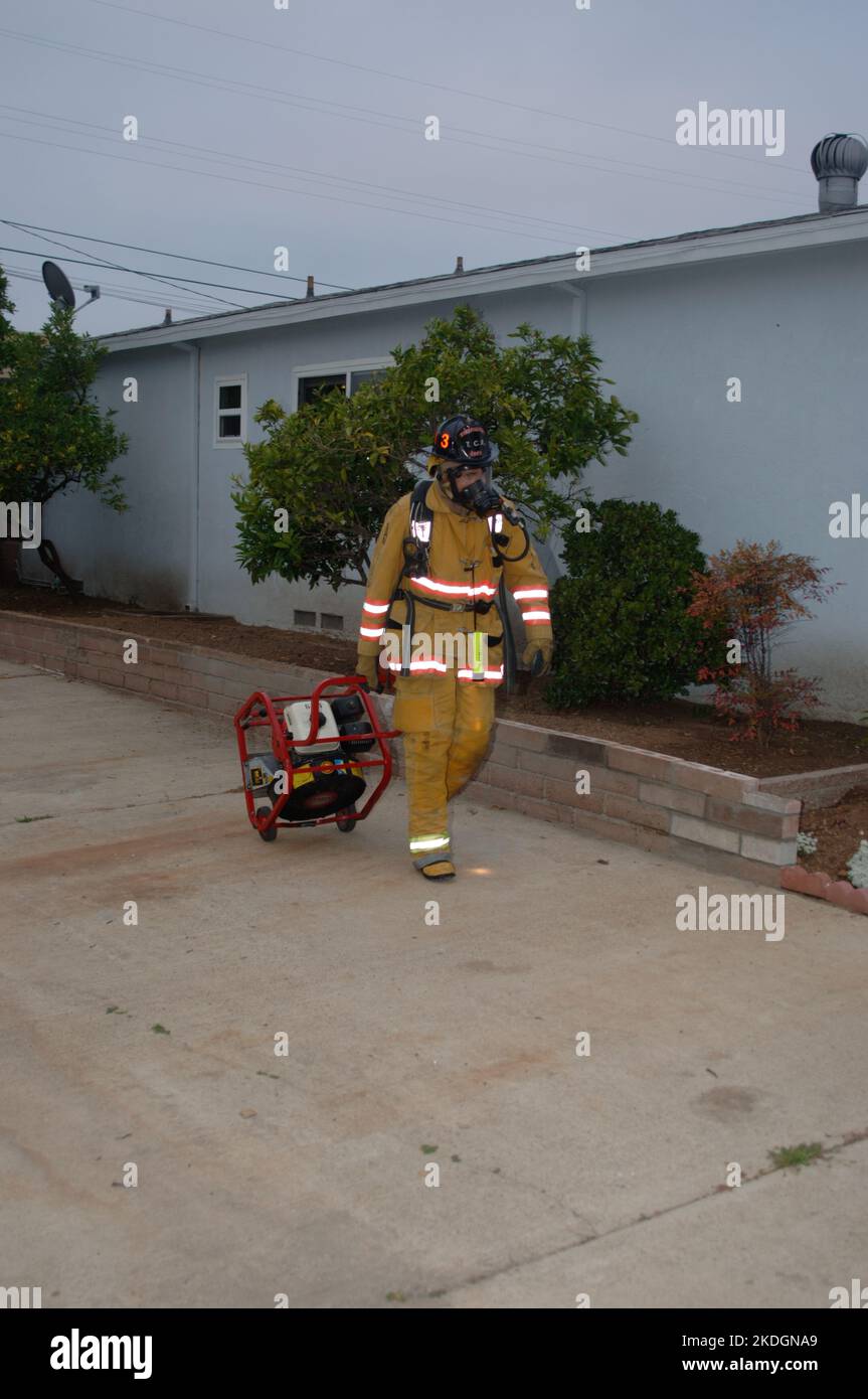 San Diego Fire-Rescue firefighter moves a blower after working a structure fire in the Kearny Mesa section of San Diego Stock Photo