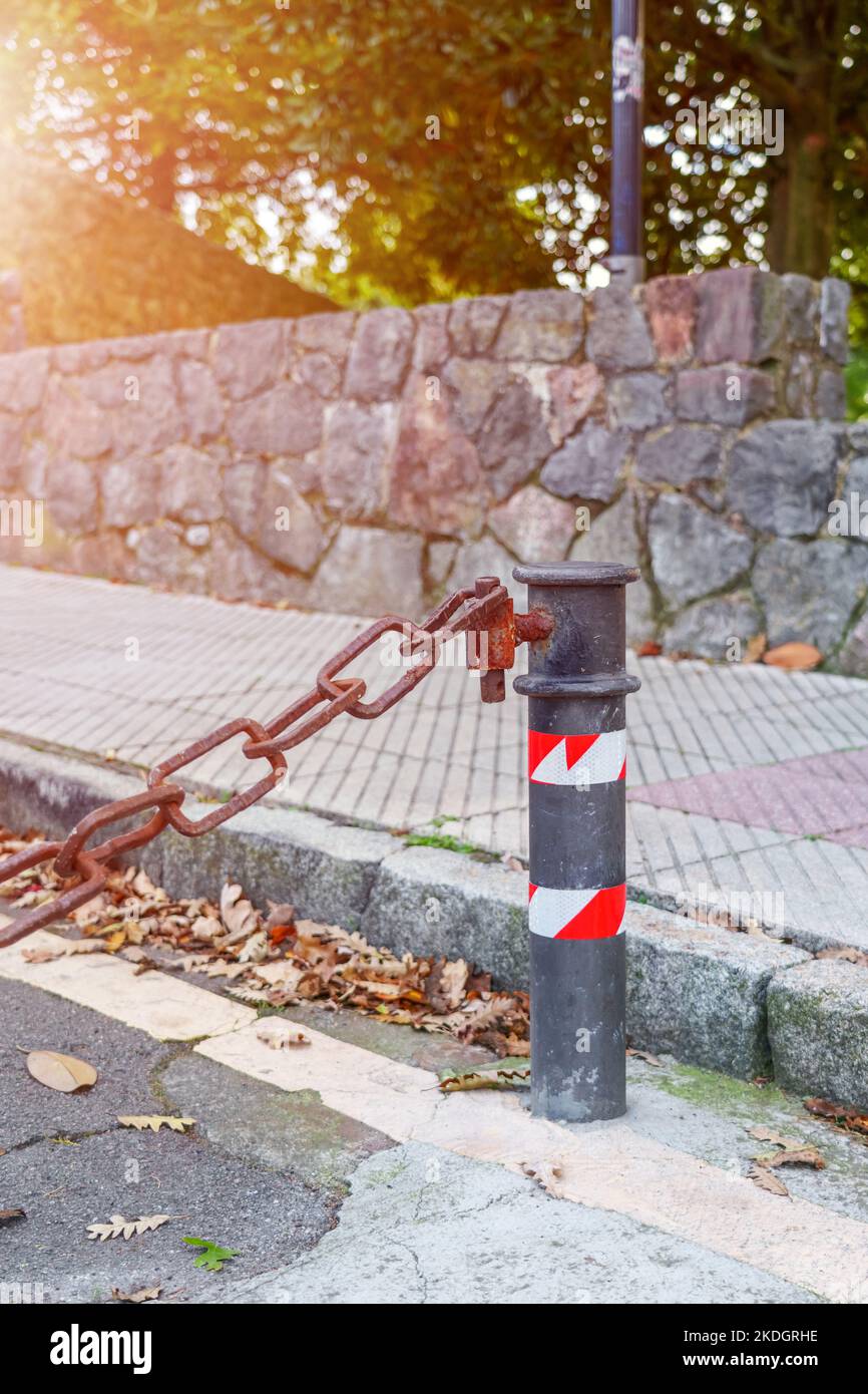 Rusty old chain connected to a pole of a private street car parking close-up Stock Photo