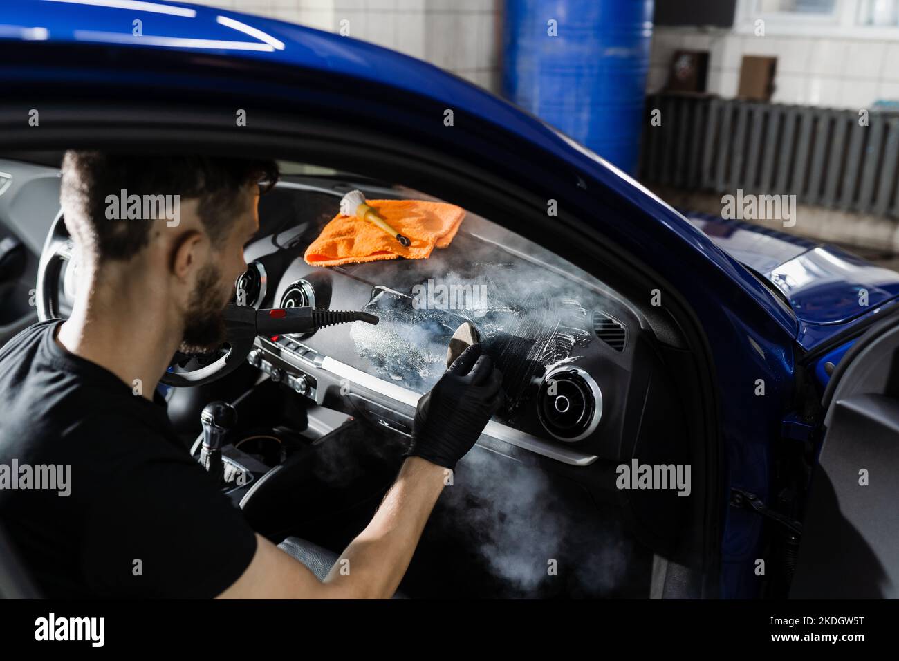 Foam and detergent cleaning interior in car using steam. Worker in auto cleaning service clean