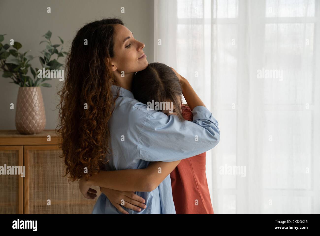 Young caring woman stands at home and hugging teenage girl needing ...