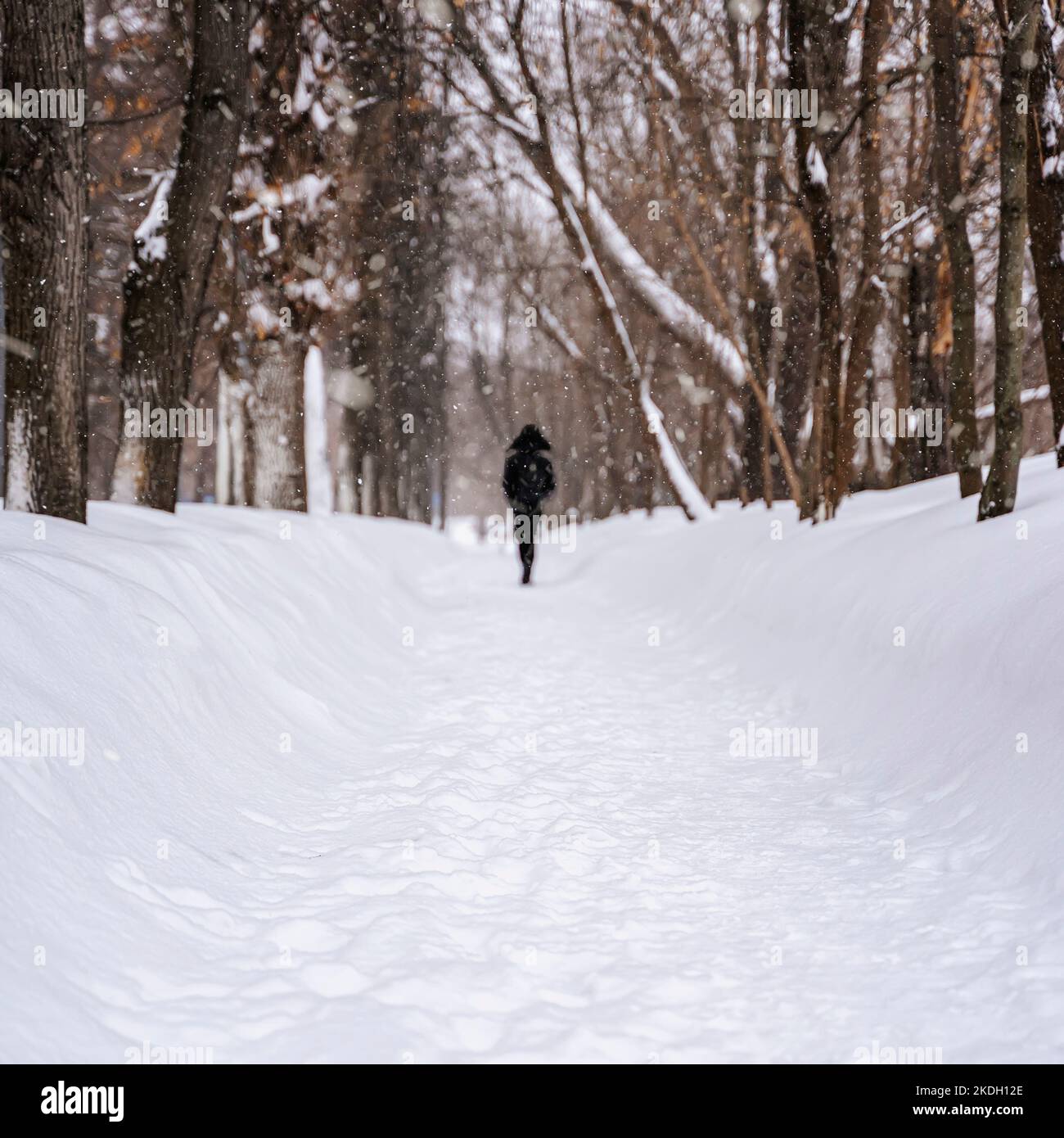 Winter. Lonely man among snowdrifts of city alley. Natural background Stock Photo