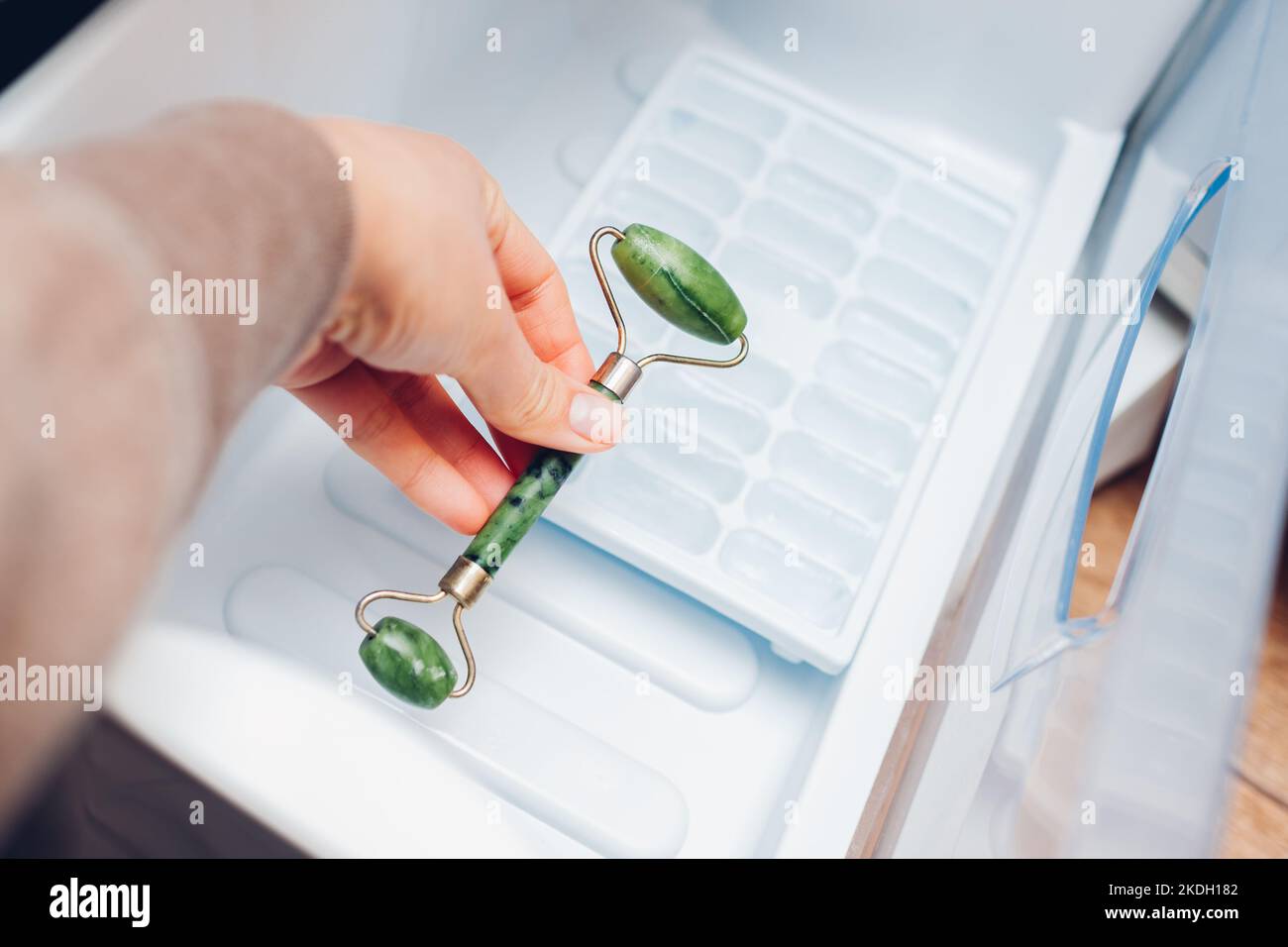 Storage of beauty tool in fridge. Woman puts jade roller for facial
