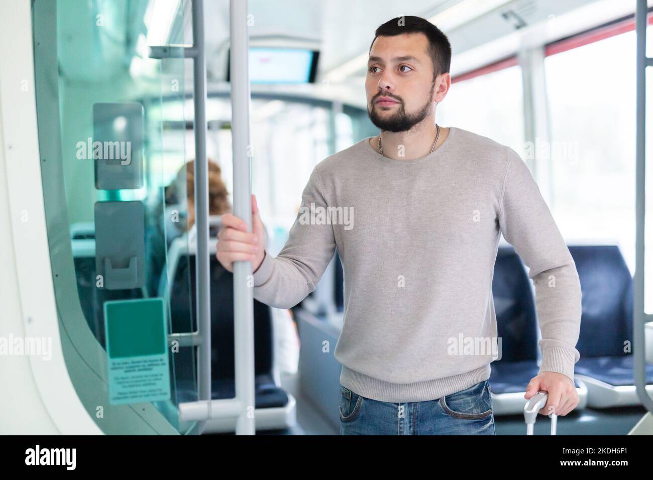 Young bearded man with suitcase riding in streetcar Stock Photo