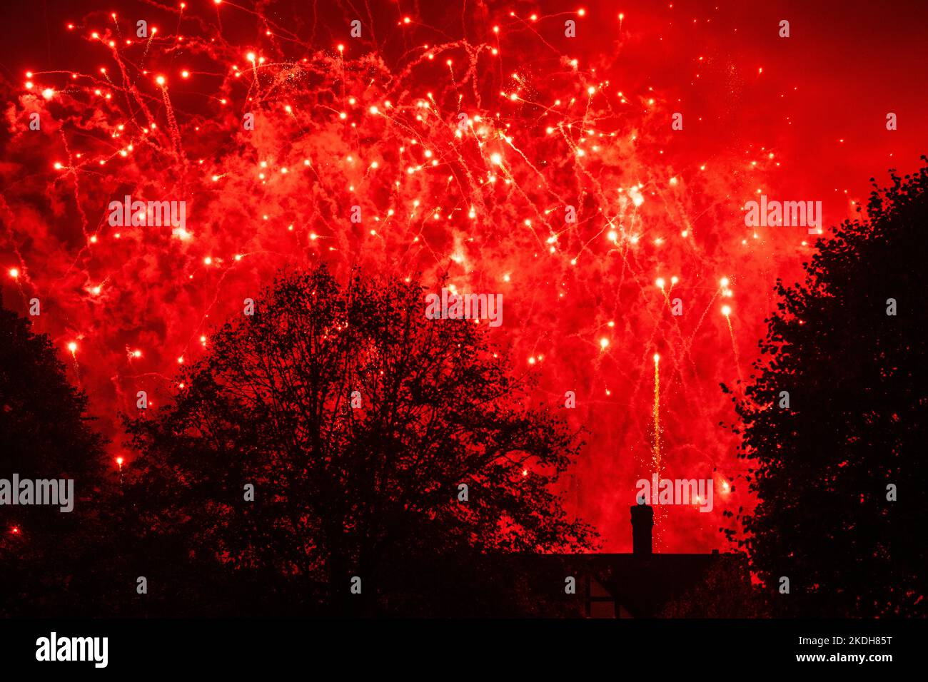 Fireworks exploding in the sky silhouette of buyer cottage and trees red and yellow Stock Photo
