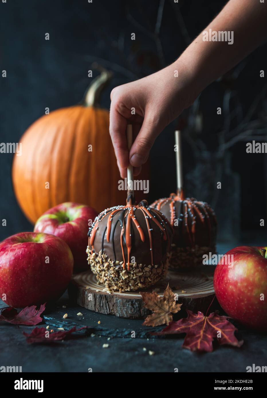Hand reaching for chocolate caramel candy apple for Hallowe'en. Stock Photo