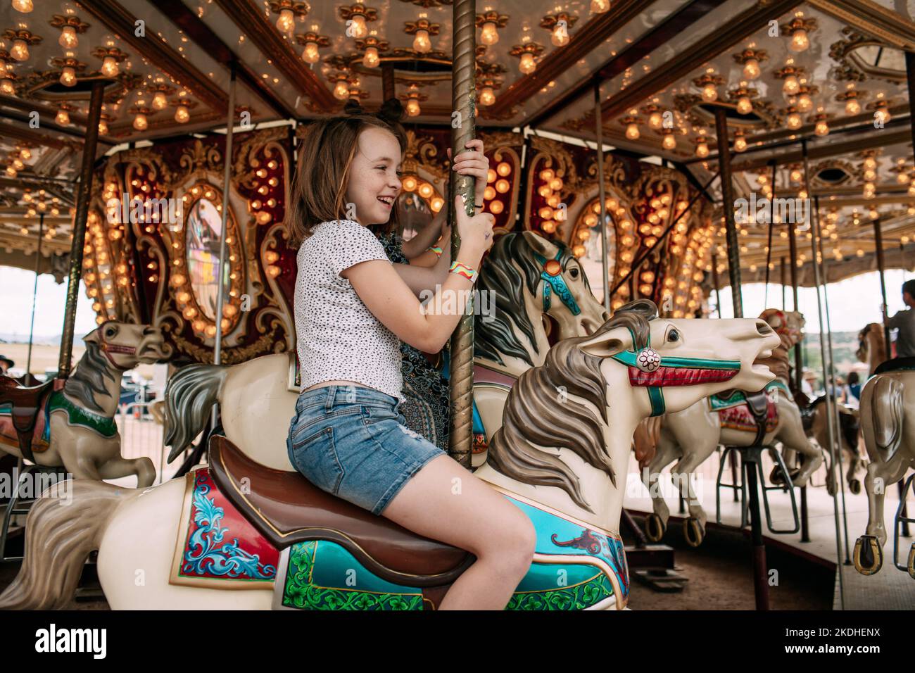 Young girl riding a carousel outside Stock Photo Alamy