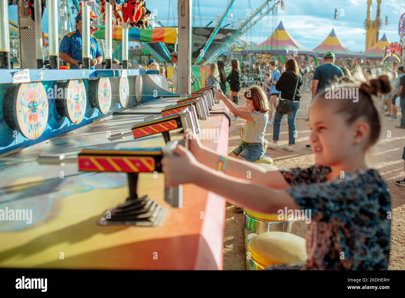 Two girls focused on carnival game on a sunny day Stock Photo
