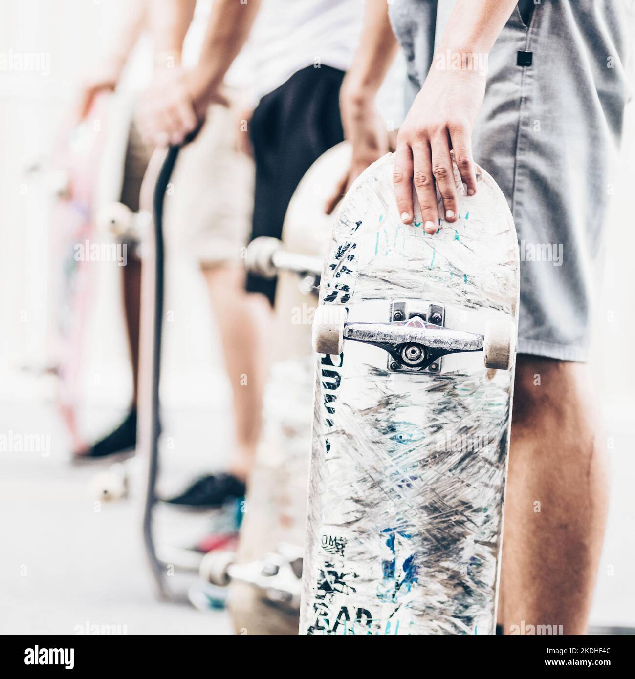 Young skateboarders skateboarding on the street. Group of friends standing in a row with skateboards in their hands. Urban life. Youth subculture. Stock Photo