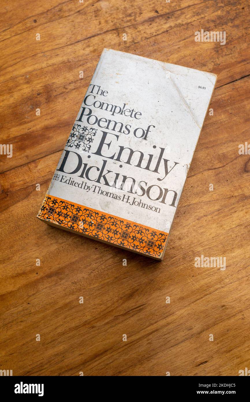 Photo of the front cover of a copy of the Complete Poems of Emily Dickinson from Harvard University Press.  On a wooden table, well read example. Stock Photo