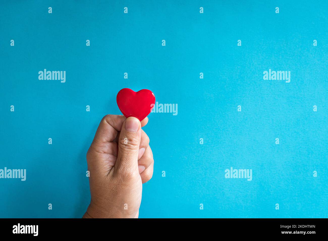 Heart health concept. Man's finger holding a red heart shape. Copy space. Stock Photo