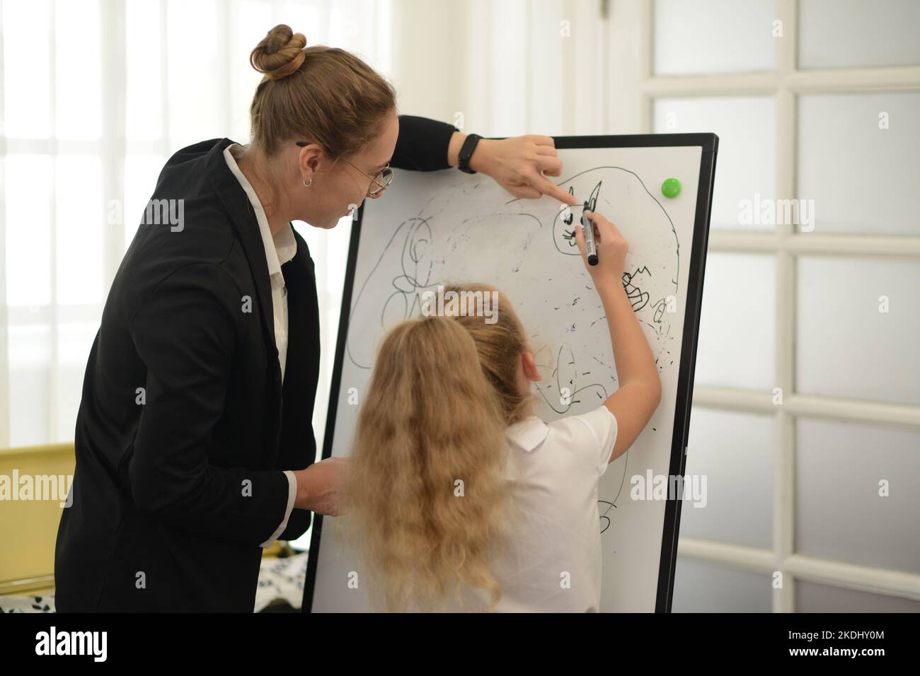 A teacher teaches her young daughter to paint with colorful pens in the ...