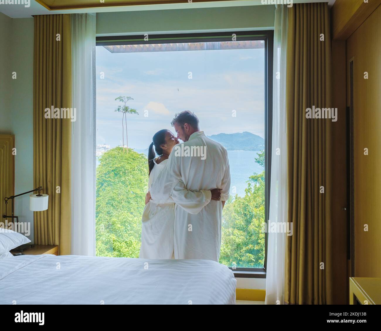 couple of men and women waking up in a hotel room looking out over the ocean.  Stock Photo