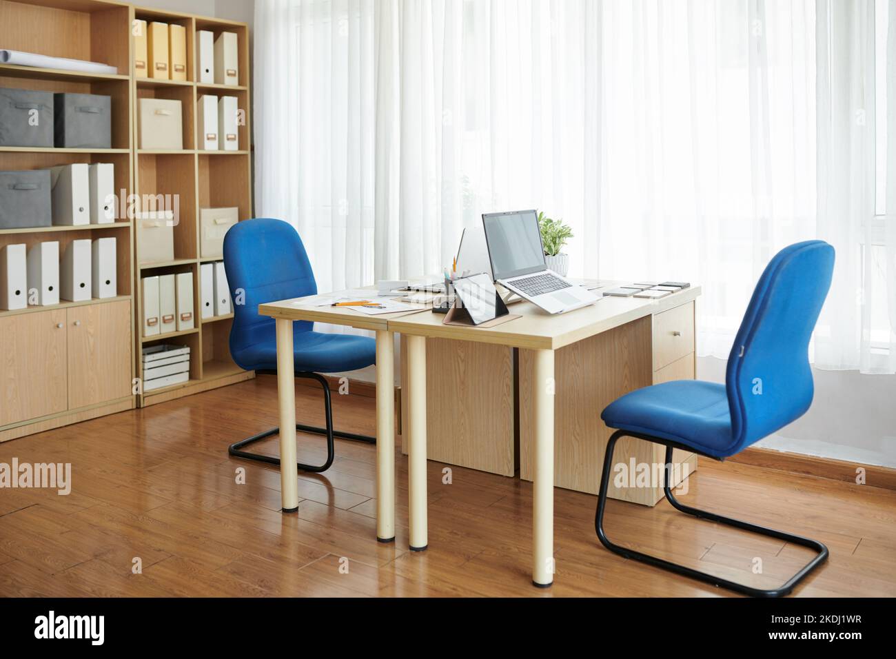 Office table with laptop, tablet and documents and two chairs facing