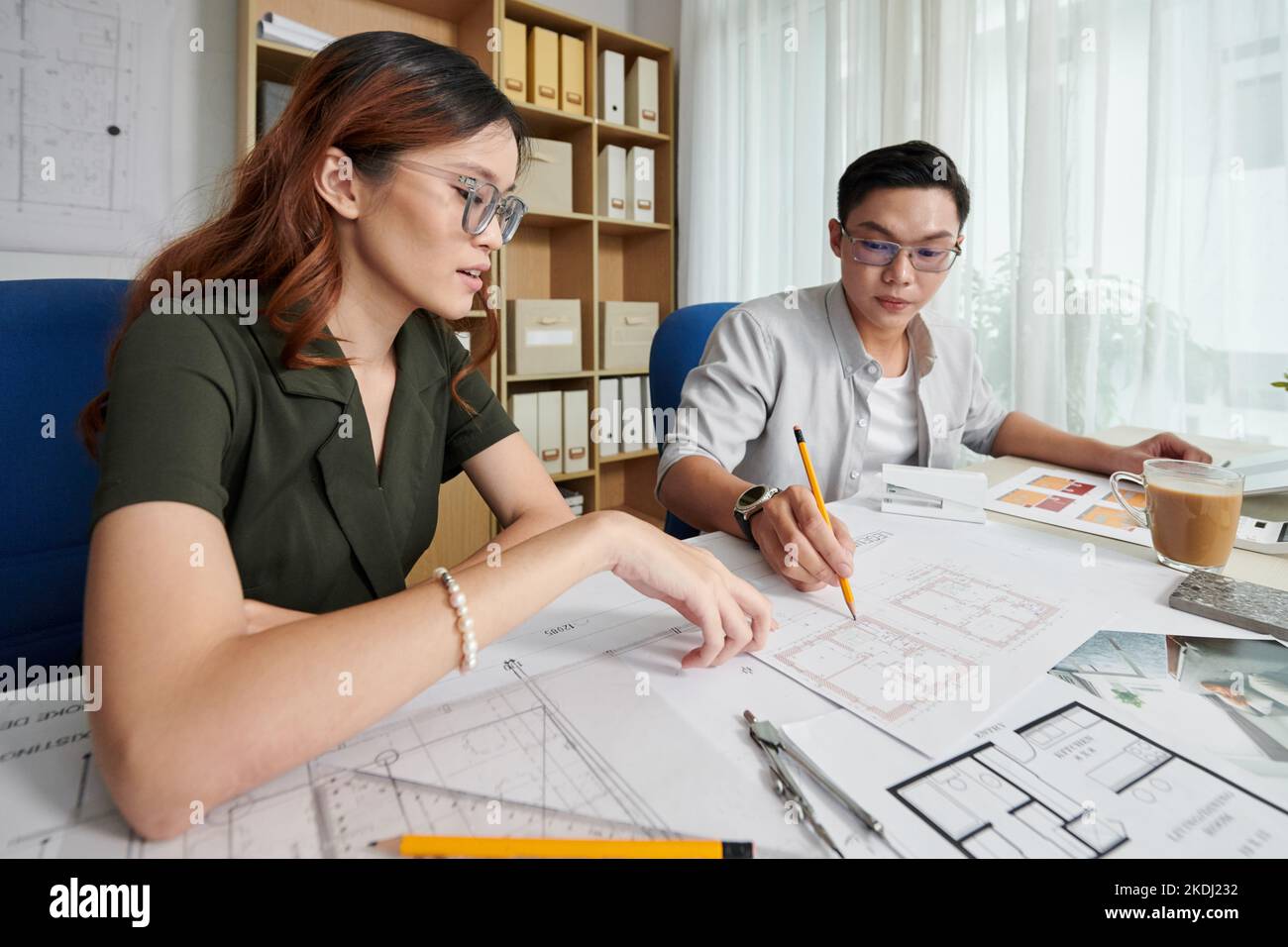 Young architects discussing building blueprint they created for client ...