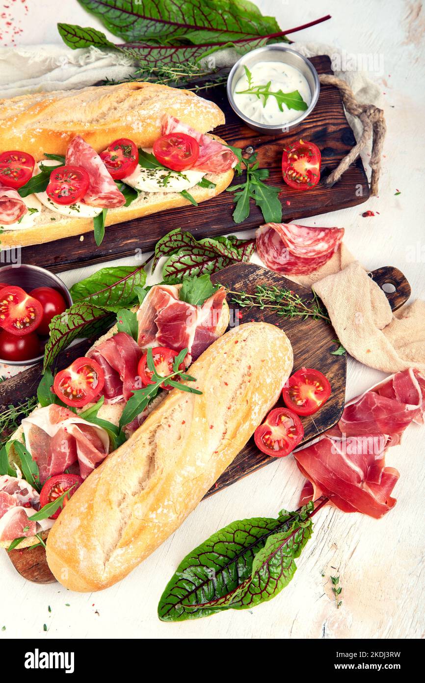 Two baguette sandwiches with salami, mozzarella cheese, lettuce