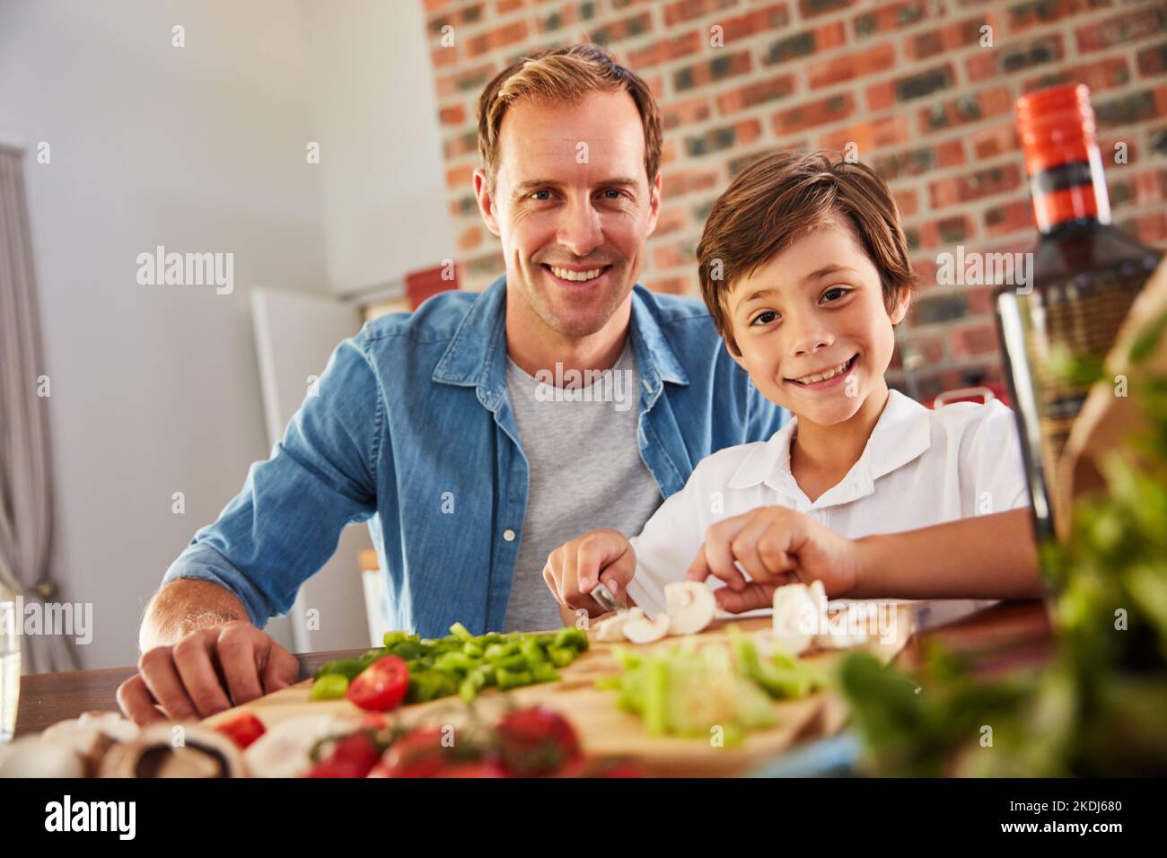 The love of cooking runs in our family. Portrait of a father and his little boy chopping vegetables in the kitchen. Stock Photo