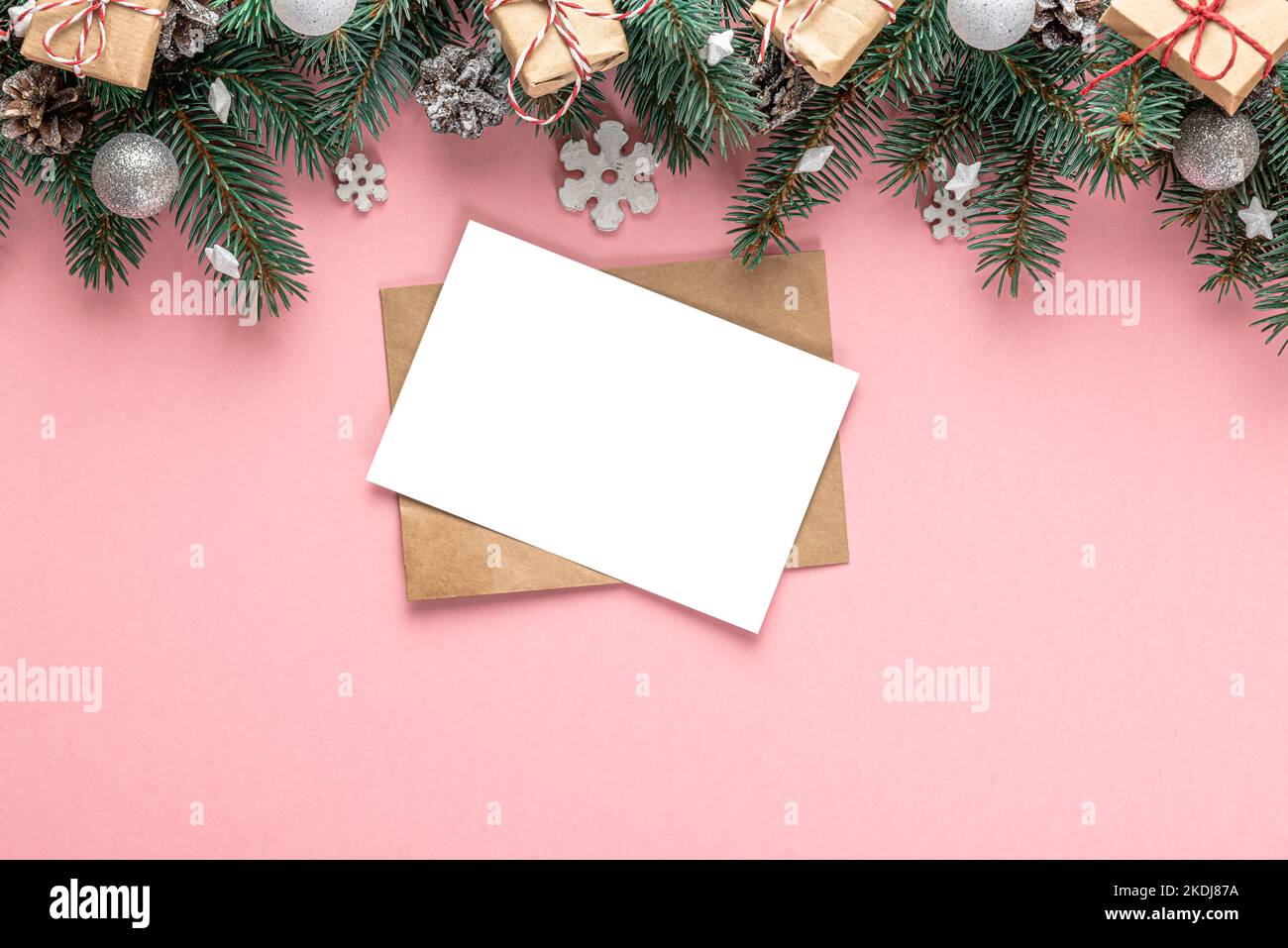 Christmas greeting card with fir tree, holiday decorations, gift boxes on pink background. Flat lay. Mock up. Top view with copy space. Festive backgr Stock Photo