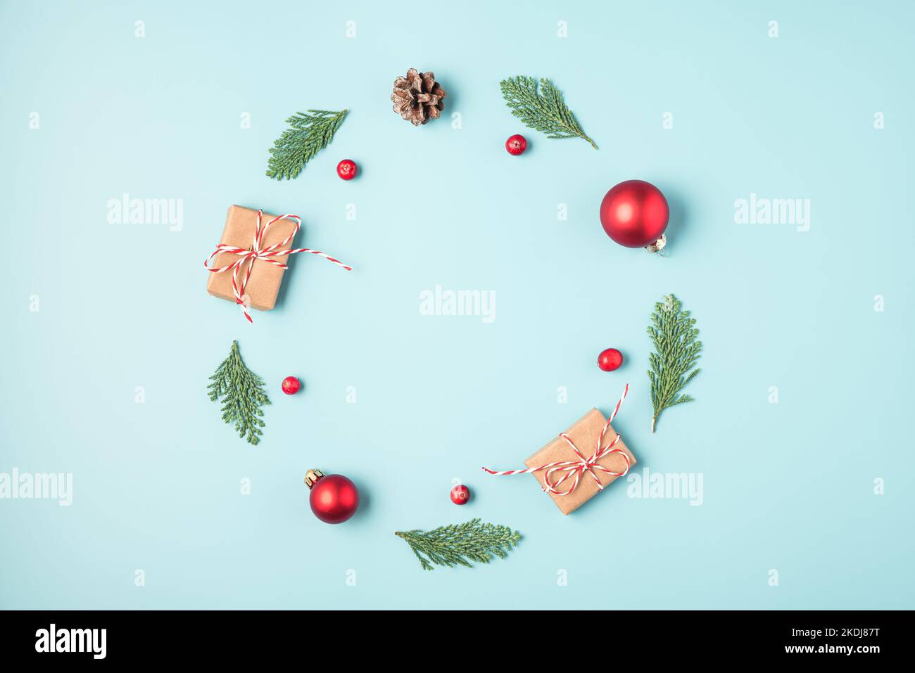 Christmas or Happy New Year frame made of fir tree branches, holiday decorations, gift boxes on blue background. Flat lay. Top view with copy space Stock Photo