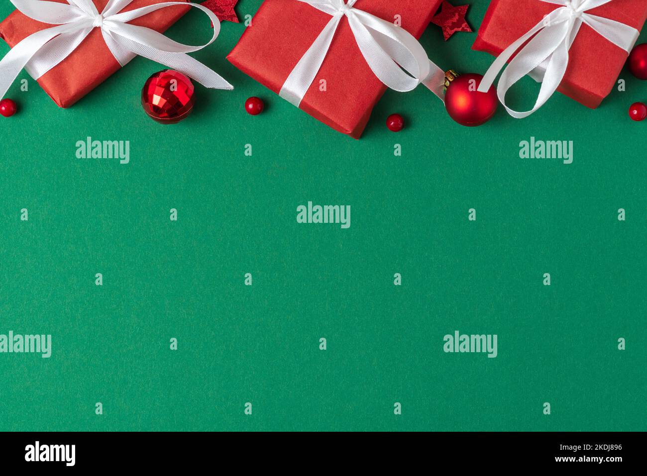 Christmas or Happy New Year background. Red gift boxes with holiday decorations on green background. Flat lay. Top view with copy space Stock Photo