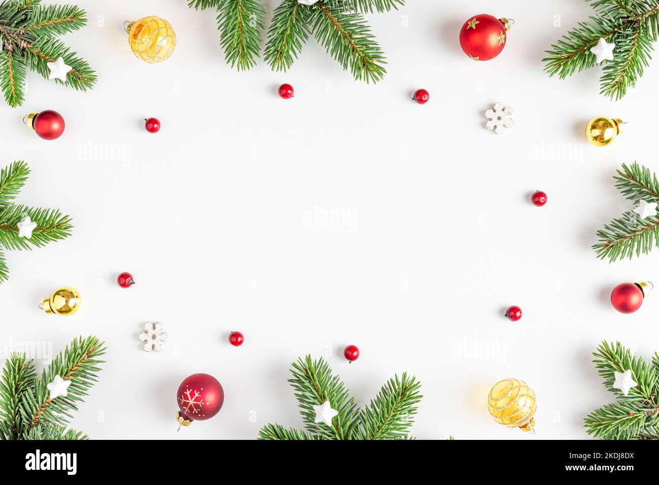 Christmas composition. Frame made of fir tree, festive decorations, red berries on white background. Flat lay. Top view with copy space. Winter holida Stock Photo
