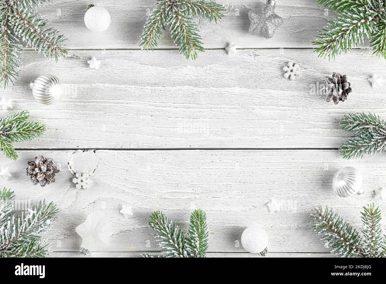 Christmas composition. Frame made of fir tree, festive silver decorations on white wooden background. Flat lay. Minimal layout. Top view with copy spa Stock Photo