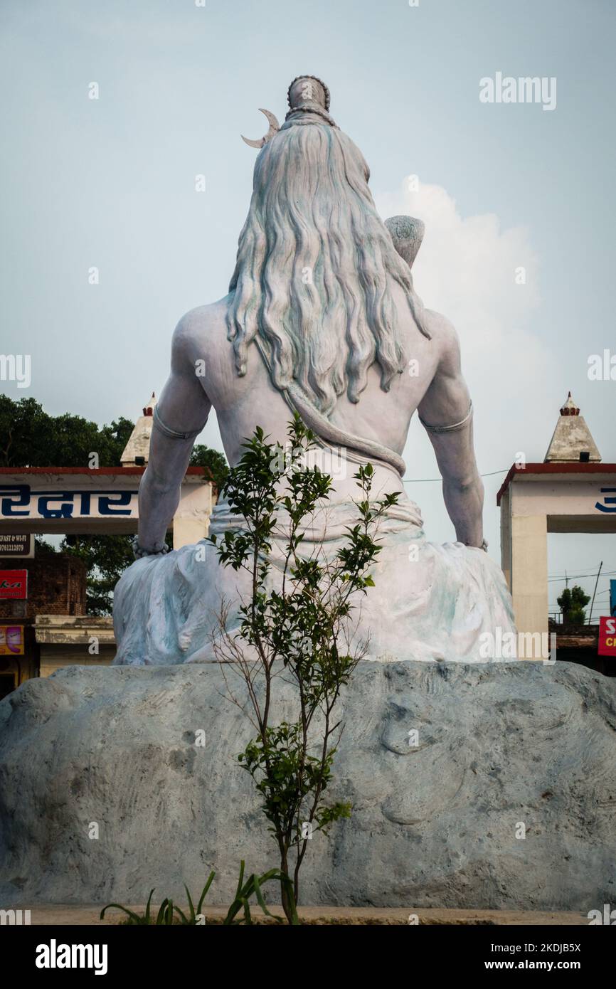 July 4th 2022 Haridwar India. Lord Shiva statue at the Haridwar railway Station with people sitting all around in waiting. Stock Photo