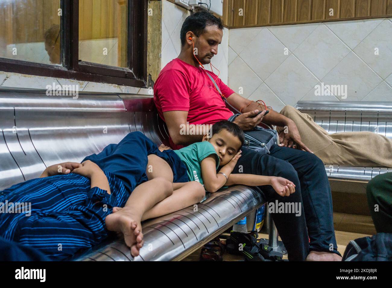 July 5th 2022 Katra, Jammu and Kashmir, India. A man with his sleeping kids at the Railway Station waiting Room. Stock Photo